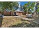 A brick, ranch-style home with a small patio and large backyard surrounded by mature trees at 334 S Revere St, Aurora, CO 80012