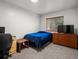 Simple bedroom with blue comforter, wooden dresser, and a large window with blinds at 6801 W 52Nd Ave, Arvada, CO 80002