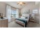 Bright bedroom featuring a ceiling fan, large window, and neutral decor at 225 Longspur Dr, Brighton, CO 80601