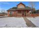 Charming home featuring a cozy front porch and beautifully landscaped front yard covered with snow at 225 Longspur Dr, Brighton, CO 80601