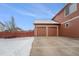 Attached two-car garage featuring carriage doors and a concrete driveway with partially fenced-in backyard at 225 Longspur Dr, Brighton, CO 80601