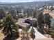 Stunning aerial view of a gray home surrounded by lush trees in a beautiful community at 31607 Broadmoor Dr, Evergreen, CO 80439