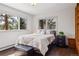 Bright bedroom featuring hardwood floors, a comfortable bed, and scenic views from the windows at 31607 Broadmoor Dr, Evergreen, CO 80439
