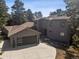 Beautiful exterior view of the house showcasing the garage and driveway surrounded by mature trees at 31607 Broadmoor Dr, Evergreen, CO 80439