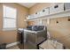 Functional laundry room with modern washer, dryer, storage shelves, and natural light at 4763 Laurelglen Ln, Highlands Ranch, CO 80130