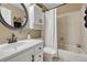 Neutral tiled bathroom with decorative round mirror, white cabinet and tub-shower combo at 1572 W Long Ave, Littleton, CO 80120