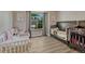 Bright bedroom featuring wood-look floors, gray curtains, and two cribs; one white and one espresso at 1572 W Long Ave, Littleton, CO 80120