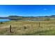 Beautiful lake view in grassy landscape under a clear blue sky, distant mountains in background at 18355 W 59Th Dr, Golden, CO 80403