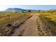 Scenic dirt path meandering through a golden, grassy landscape with distant mountain views under a bright sky at 18355 W 59Th Dr, Golden, CO 80403