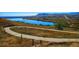 Picturesque walking path winding through a scenic landscape with a lake and rolling hills under the blue sky at 18355 W 59Th Dr, Golden, CO 80403