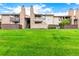 Exterior view of a well-maintained townhouse building with green grass, rock accents, and a blue sky at 7750 W 87Th Dr # C, Arvada, CO 80005