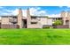 Low angle view of a well-maintained townhouse building with green grass and a stone chimney at 7750 W 87Th Dr # C, Arvada, CO 80005