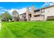 Exterior view of condos with stone chimneys, wood siding, and well-manicured lawn and blue sky at 7750 W 87Th Dr # C, Arvada, CO 80005
