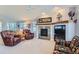 Cozy living room with fireplace, mantle, large windows, and comfortable leather chairs at 8233 E 149Th Dr, Thornton, CO 80602
