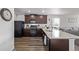 Modern kitchen featuring dark wood cabinets, granite countertops, stainless steel appliances, and adjacent living room at 350 Mesa Ave, Lochbuie, CO 80603
