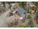 A-frame style house with a covered porch and outdoor seating surrounded by lush forest and a neighboring house at 356 Castlewood Dr, Evergreen, CO 80439