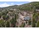 A-frame style house nestled in wooded area with a long dirt driveway and neighboring houses at 356 Castlewood Dr, Evergreen, CO 80439