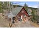 Aerial view of a cozy home with a large deck and outdoor dining area, surrounded by trees at 356 Castlewood Dr, Evergreen, CO 80439