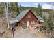 Aerial view of charming home with a deck, and grill surrounded by lush trees at 356 Castlewood Dr, Evergreen, CO 80439