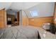 Attic bedroom with wood-paneled walls, skylight, stylish chair and rug, and wood floors at 356 Castlewood Dr, Evergreen, CO 80439