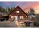 Charming two-story cabin with a wooden exterior, spacious deck, and picturesque sunset backdrop at 356 Castlewood Dr, Evergreen, CO 80439