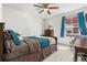 Comfortable bedroom featuring a ceiling fan, window with blue curtains and carpeted floors at 10859 E 25Th Dr, Aurora, CO 80010