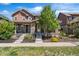 Inviting home with covered porch and stone details, complemented by green landscaping and a sunny sky at 10859 E 25Th Dr, Aurora, CO 80010