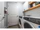 Well-lit laundry room with white cabinets, gray subway tile, and modern washer and dryer at 4630 Copeland Cir # 201, Highlands Ranch, CO 80126