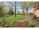 Beautifully landscaped front yard with green grass, mature trees, and charming wooden chairs at 3665 Estes St, Wheat Ridge, CO 80033