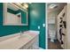 Bright bathroom featuring a modern sink with a stylish mirror and vibrant teal walls at 5773 W 76Th Dr, Arvada, CO 80003