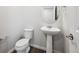 A clean half bathroom with a pedestal sink, toilet, and modern fixtures at 2186 Flower Blossom Ave, Brighton, CO 80601
