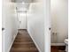 Hallway with hardwood floors leading to a half bathroom and the front door at 2186 Flower Blossom Ave, Brighton, CO 80601