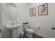 Bright powder room features a pedestal sink, modern fixtures, and elegant art at 730 Cottonwood Ave, Bennett, CO 80102