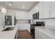 Bright kitchen features white cabinets, quartz countertops, stainless appliances and hardwood floors at 730 Cottonwood Ave, Bennett, CO 80102