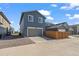 View of the rear of the home with a two-car garage and a concrete driveway and gravel landscaping at 730 Cottonwood Ave, Bennett, CO 80102