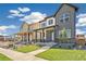 New construction home featuring a covered porch, stone accents, and professionally landscaped yard at 21022 E 63 Dr, Aurora, CO 80019
