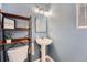 Charming half bath with light blue walls, white fixtures, and an industrial-style shelf at 7648 S Sicily Way, Aurora, CO 80016
