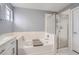 Bright bathroom features a soaking tub with shower and white vanity with sink at 7648 S Sicily Way, Aurora, CO 80016