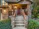 Inviting front porch with stone columns, wooden railing, and a charming wreath on the front door at 7648 S Sicily Way, Aurora, CO 80016