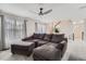 Comfortable living room featuring an oversized gray sofa, ceiling fan and staircase at 7648 S Sicily Way, Aurora, CO 80016