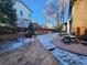 A snowy back yard with patio, outdoor table and chairs, fire pit, and mature trees at 8850 W Cannes Dr, Littleton, CO 80127