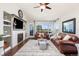 Inviting living room featuring a cozy fireplace, ceiling fan, and comfortable leather seating at 16485 E 117Th Ave, Commerce City, CO 80022