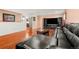 Living room with hardwood floors, black leather couch, glass coffee table, and entertainment center at 1027 Norfolk St, Aurora, CO 80011
