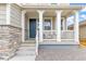 Inviting front porch with stone accents, white pillars, and a blue front door, adding curb appeal at 16108 Red Bud Loop, Parker, CO 80134