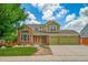 Inviting two-story home with a brick facade, lush lawn, and a three car attached garage at 2882 Signal Creek Dr, Thornton, CO 80241