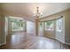 Open living room boasts a chandelier, hardwood flooring, and expansive windows at 2882 Signal Creek Dr, Thornton, CO 80241
