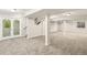 Large finished basement area with support beams, neutral carpet, stairs, and a door to the outside at 6429 S Jamaica Cir, Englewood, CO 80111