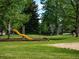 Neighborhood playground with yellow slide surrounded by mature green trees at 15395 E Penwood Pl, Aurora, CO 80015
