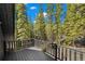 A balcony with wooden railings overlooking a tall and full pine forest at 46 Silver Creek Rd, Idaho Springs, CO 80452