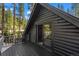 Balcony of black cabin, overlooking forest, with open glass doors to inside at 46 Silver Creek Rd, Idaho Springs, CO 80452